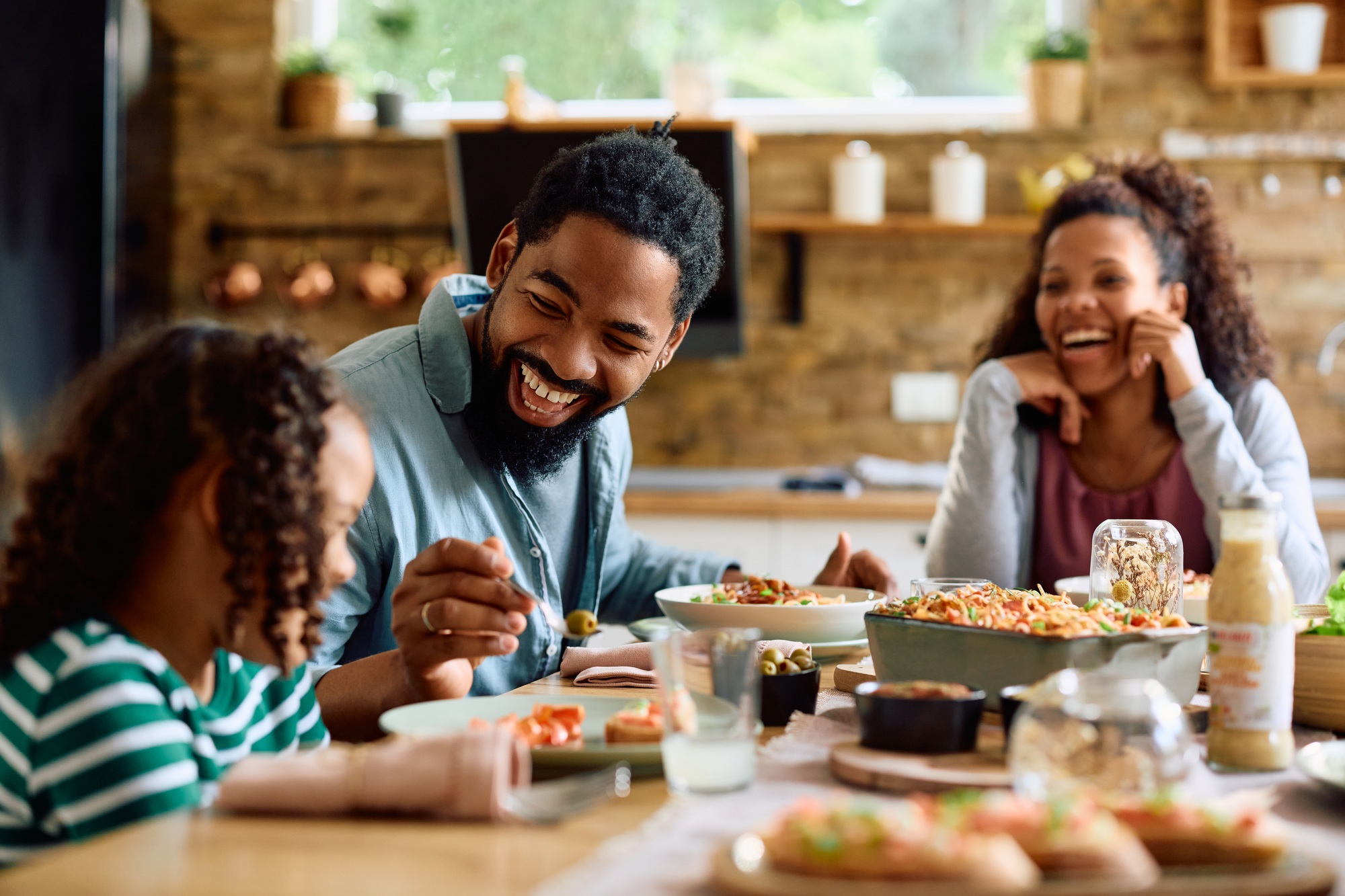 Happy black family having fun while eating lunch at dining table.